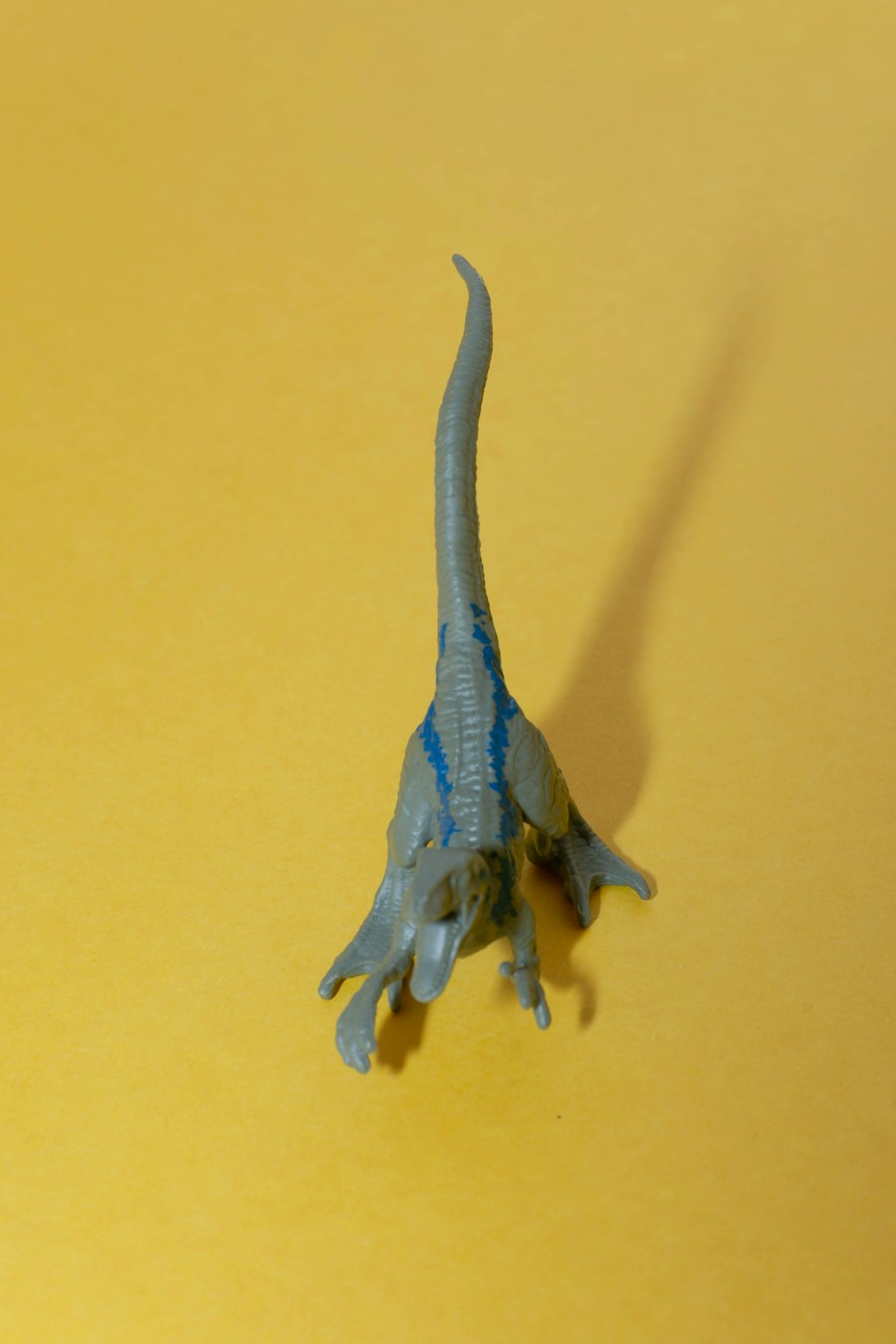Blue and green dinosaur figure on a yellow background
