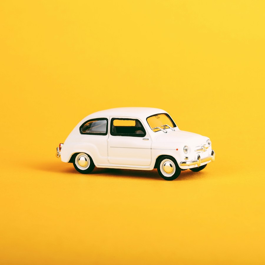 White miniature city car against a yellow background