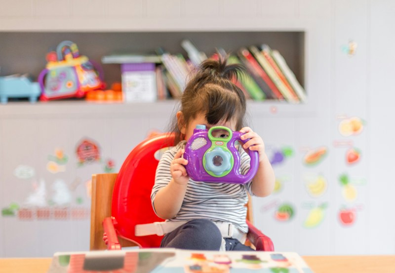 Child playing with a colourful toy camera
