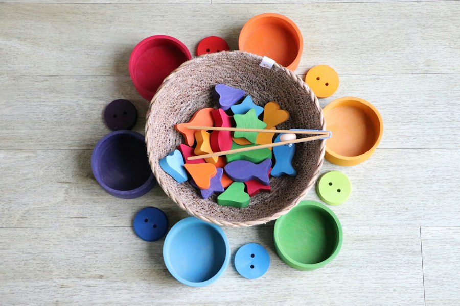 Rainbow-coloured wooden bowls around a basket of sorting pieces
