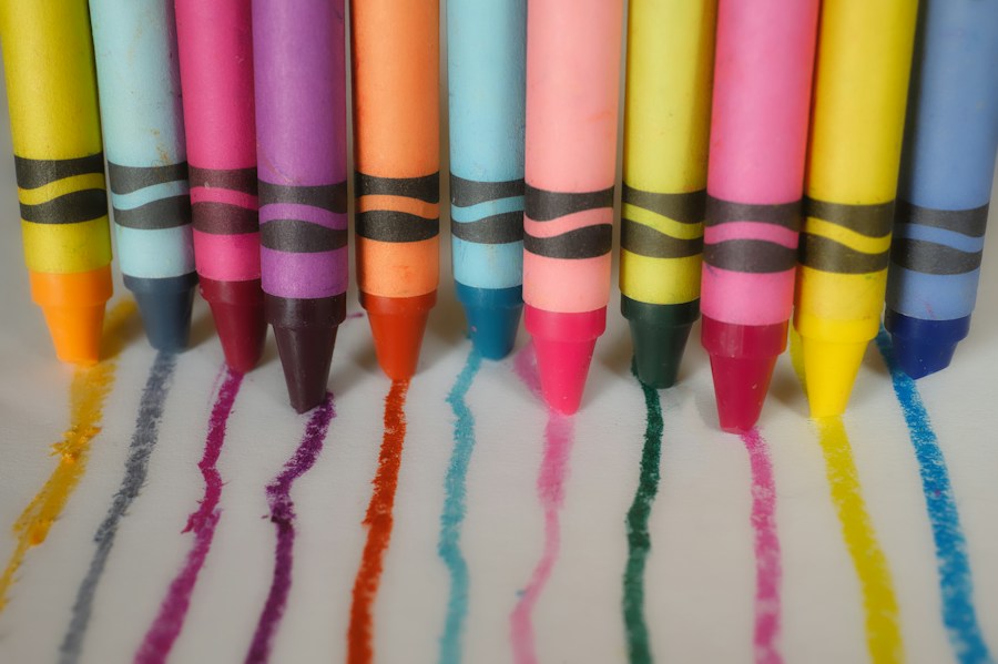 Colourful wax crayons making matching marks on white paper